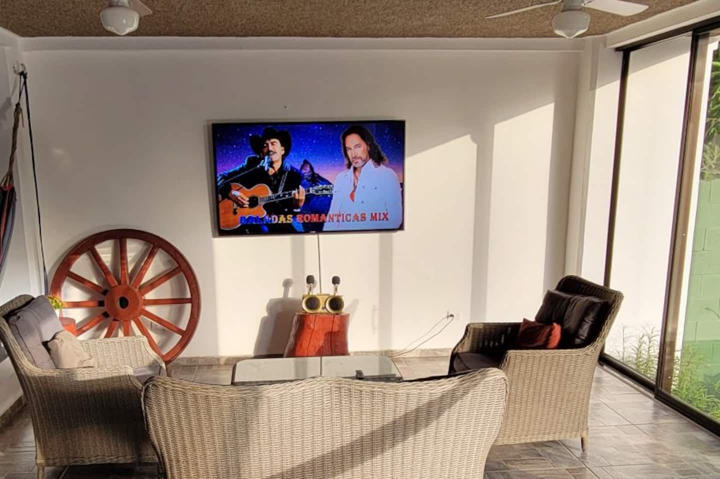 El Cocal's living room with a wall-mounted 65-inch TV showing a karaoke track, two microphones on the table